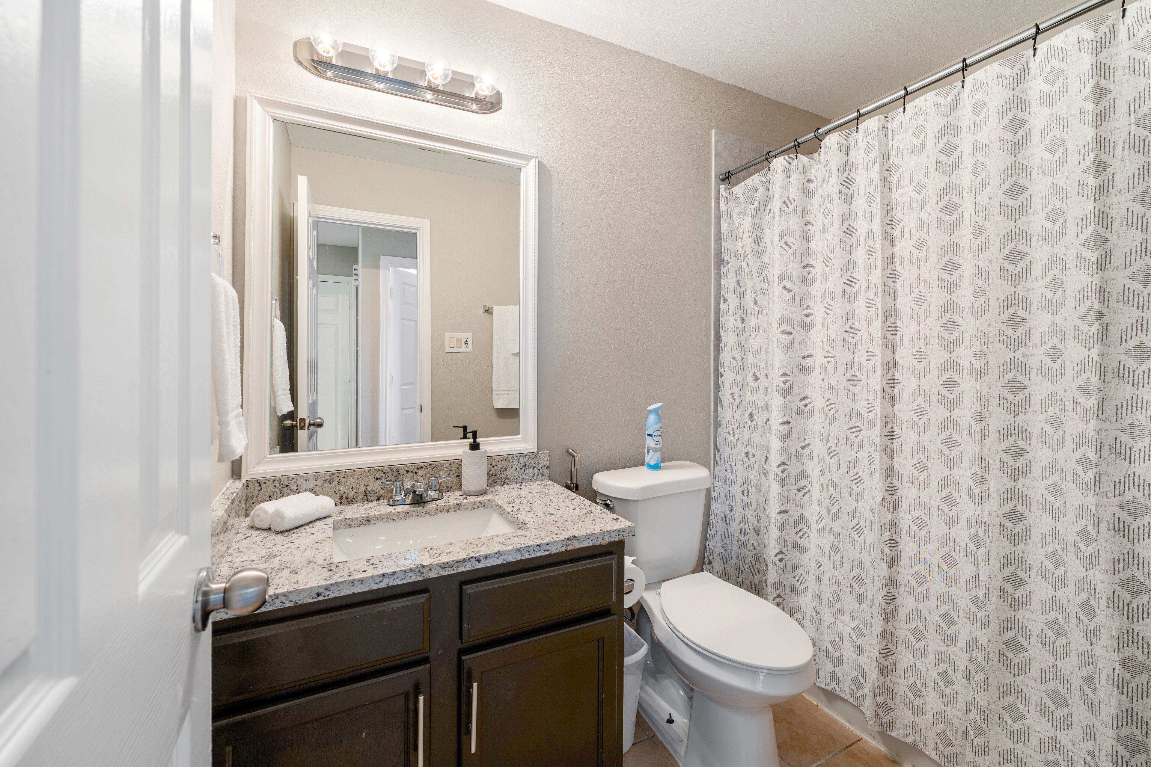 Une salle de bain équipée d’un lavabo, d’un miroir, de toilettes et d’un rideau de douche.