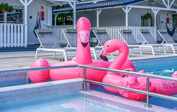 A swimming pool with pink flamingo inflatable floats.