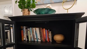 A black bookshelf with books, board games, and a decorative bowl. - Lake Views & Fall Colors | Cozy Cottage + Kayaks (Jay)