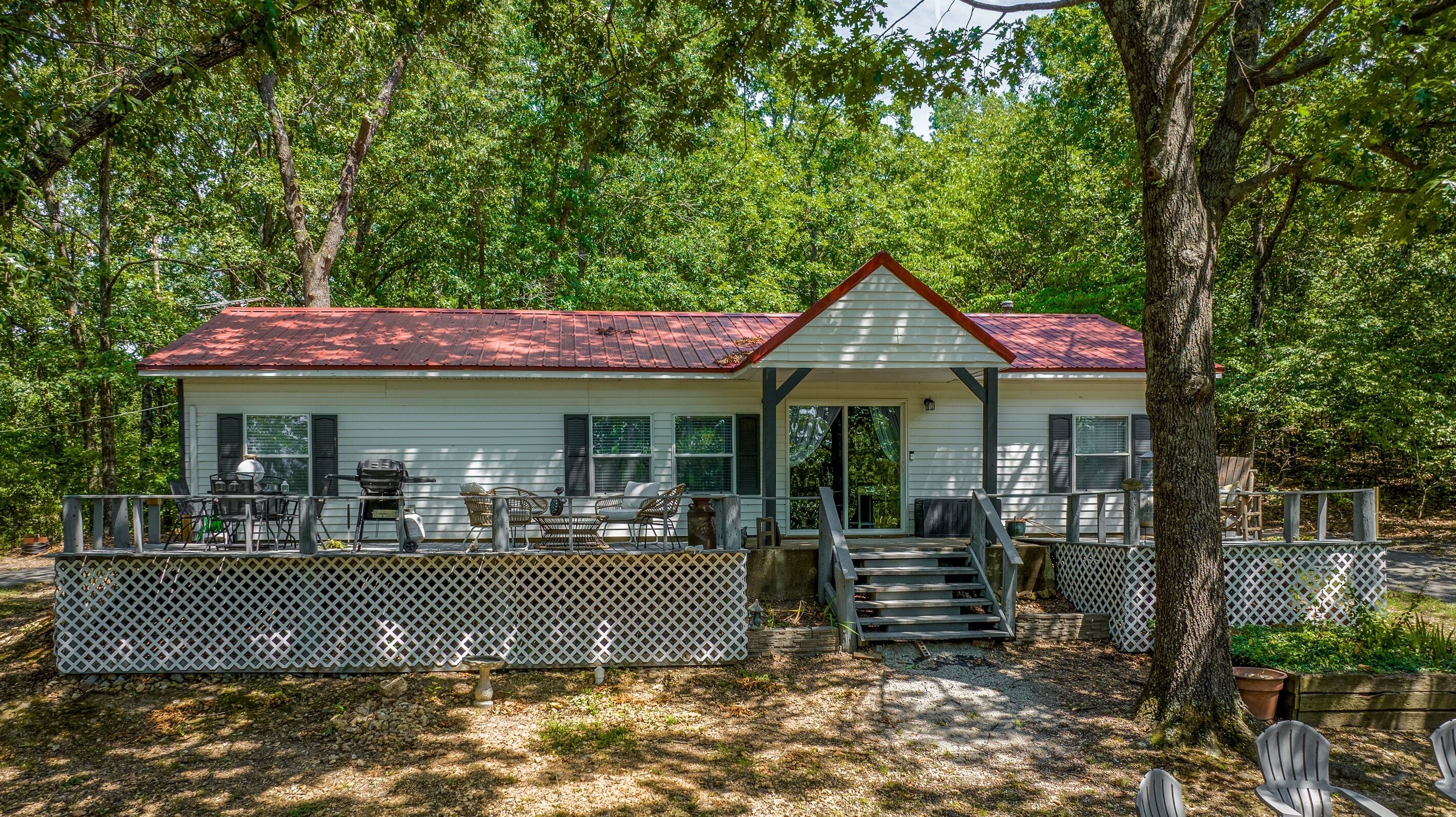 A cabin with a porch, outdoor seating, and a grill.