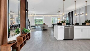 Una cocina moderna con una isla central, muebles blancos y electrodomésticos de acero inoxidable.