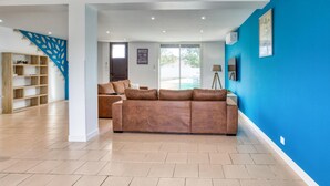 A modern living room with a brown sofa, a wooden bookshelf, and a blue accent wall. - Stunning home in Albi (Albi)