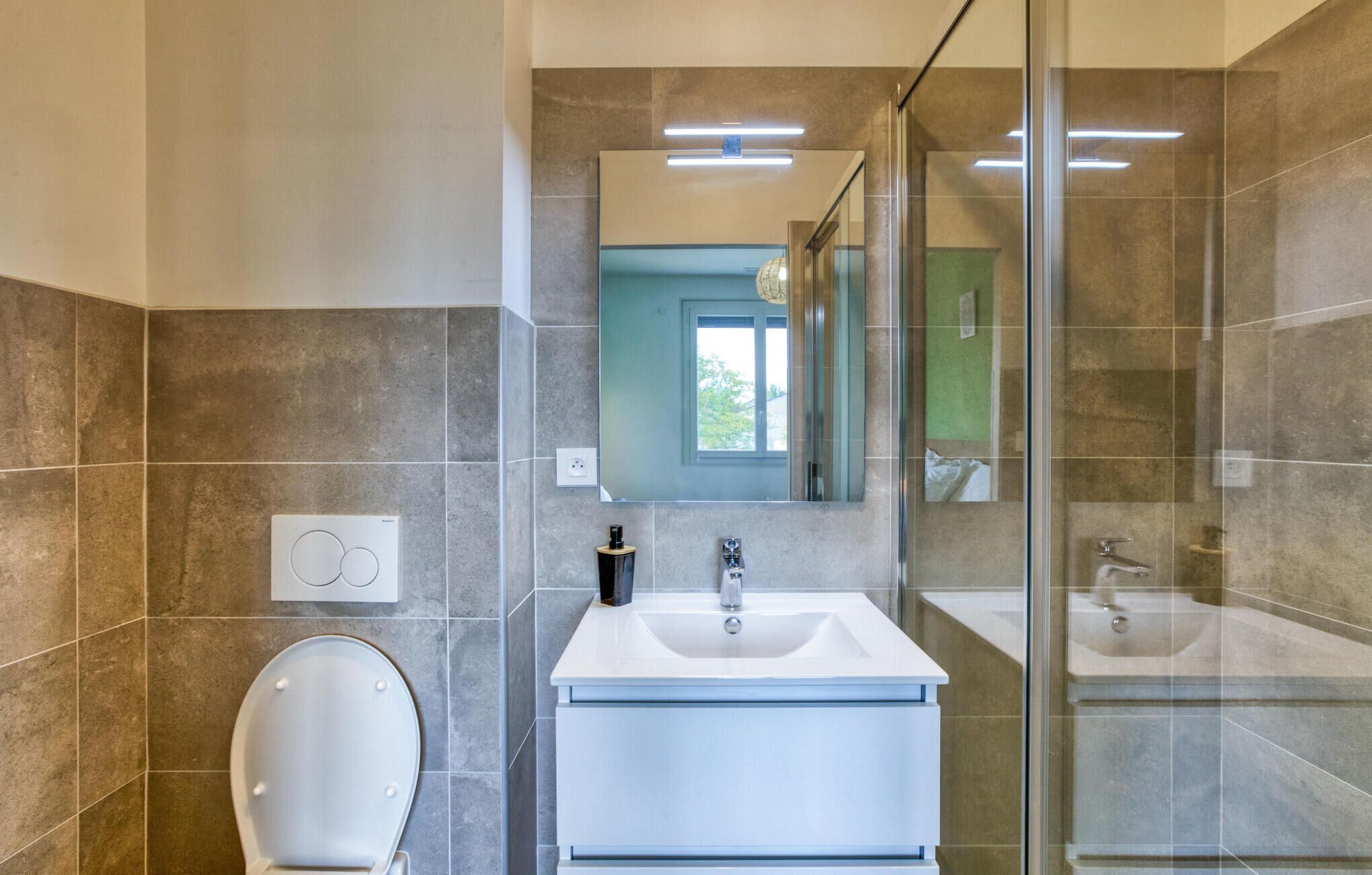 A modern bathroom with a toilet, sink, and glass shower enclosure.