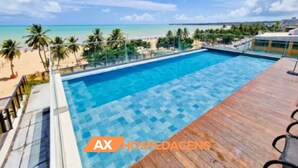 Una piscina con muelle de madera, rodeada de palmeras y vista al mar.