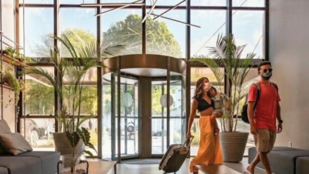 Un hall espacioso con ventanas amplias, una zona de estar central y plantas en macetas.
