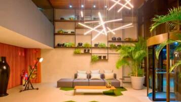 A modern lobby with a sofa, coffee table, and potted plants.
