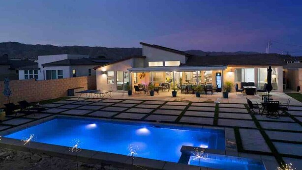 A modern house with a swimming pool, outdoor seating, and a well-lit patio area. - Fun gameroom,big yard,pool+spa,fire pit (Desert Hot Springs)