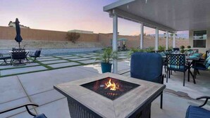 An outdoor patio with a fire pit, seating, and a view of the desert landscape. - Fun gameroom,big yard,pool+spa,fire pit (Desert Hot Springs)