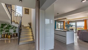 Et moderne interiør med trappe, køkkenø og siddeområde.
