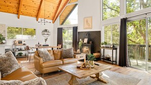 Una sala de estar amplia con techo alto, ventanas grandes, chimenea y un rincón de estar acogedor.
