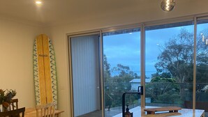A modern kitchen with a marble countertop, a built-in sink, and a large window overlooking a deck. - Brand new upside down townhouse with ocean views (Ventnor)