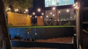 A modern house with a large glass window, a wooden fence, and a garden with gravel and plants. - Brand new upside down townhouse with ocean views (Ventnor)