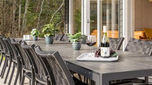 Une table à manger dressée pour six personnes, avec des chaises, une bouteille de vin et un plateau de raisins.