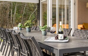 Enjoy a meal al fresco at this outdoor dining area, surrounded by lush greenery and a serene view.