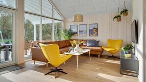 Un salon moderne avec une grande fenêtre, un canapé, un fauteuil jaune et une table basse.
