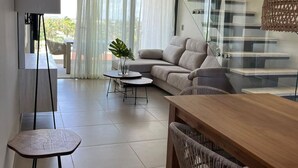 A modern living room with a sofa, a coffee table, and a dining table. - 2 Bedroom Penthouse - with Rooftop Picuzzi.3 min to the beach!! (Punta Cana)