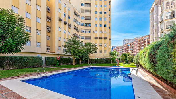 A swimming pool surrounded by apartment buildings, with a clear sky above.