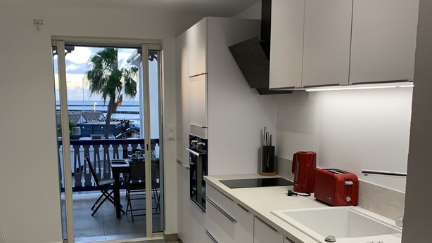 Eine moderne Küche mit weißen Schränken, einem roten Toaster und Blick auf einen Essbereich mit Tisch und Stühlen.