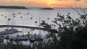 Ein Yachthafen mit mehreren angestuften Booten, umgeben von ruhigem Wasser und einem Sonnenuntergang im Hintergrund.