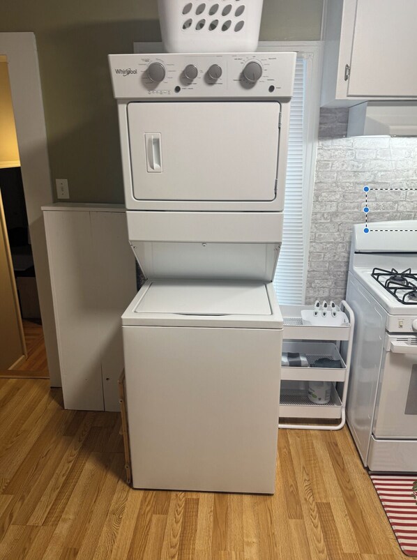 Una cocina con lavadora y secadora apiladas, un refrigerador y una estufa a gas.