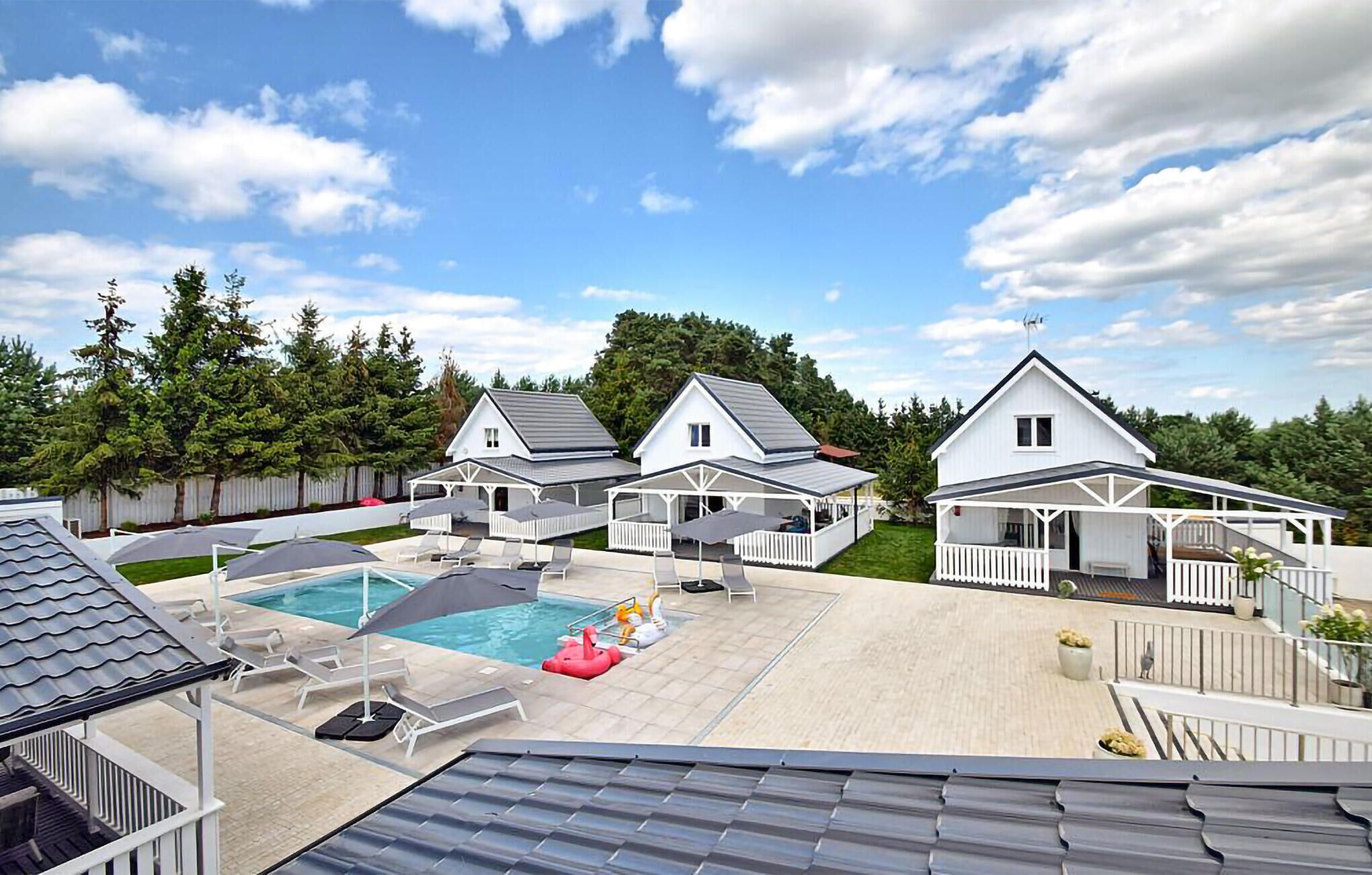 A residential area with three houses, a swimming pool, and outdoor seating areas.