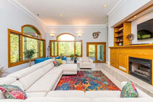 A spacious living room with a large sectional sofa, a fireplace, and a television.