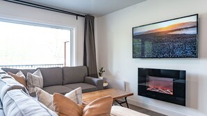 Una sala moderna con un sofá gris, una mesa de centro de madera y una chimenea.