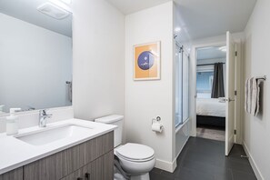 A modern bathroom with a sink, toilet, and shower. There is a framed picture on the wall and a towel rack. - The RendezView by Revelstoke Vacations (Revelstoke)