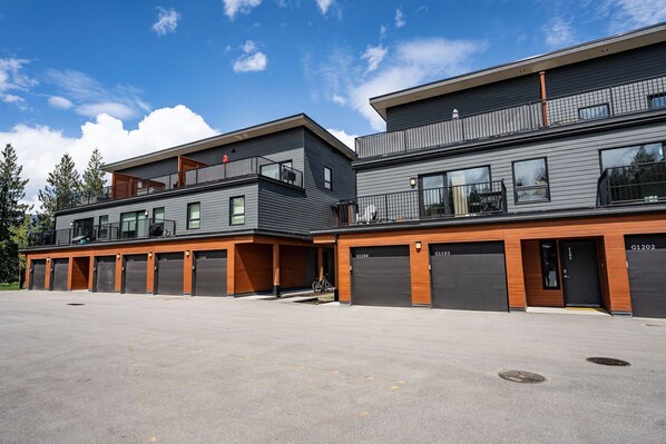 A modern building with two-story parking garages and a covered outdoor area. - The RendezView by Revelstoke Vacations (Revelstoke)