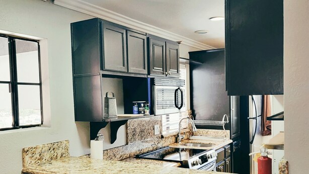 A kitchen with granite countertops, a built-in stove, and dark cabinetry. - Fully Furnished Style 2 BHK - 1 BATH Apt in San Diego Poway-Miramar with Parking (Poway)