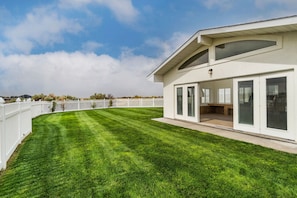 A modern house with a well-maintained lawn, a white picket fence, and a large sliding glass door leading to an outdoor area.