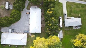 An aerial view of a property with a large white building, a smaller attached structure, and a dock extending into a body of water. - Professor Rousseau's Manatee Bay (Crystal River)