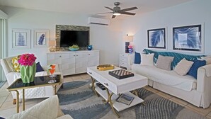 A modern living room with a white sofa, a coffee table, a TV, and artwork on the walls.