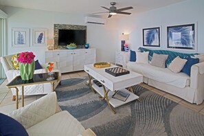 A modern living room with a white sofa, a coffee table, a TV, and artwork on the walls. - Ocean Views | Near Magen’s Bay w/ Pool & Generator (Northside)
