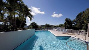 A swimming pool with clear blue water, surrounded by lounge chairs and palm trees. - Ocean Views | Near Magen’s Bay w/ Pool & Generator (Northside)