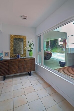Een kamer met een groot raam, een houten kast en een spiegel met een decoratieve lijst.