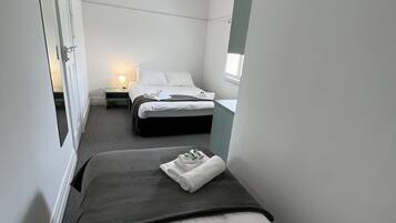 A hotel room with two beds, a ceiling fan, a bedside lamp, and a window.