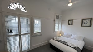 Une chambre d’hôtel avec un lit, une table de chevet, une lampe et une fenêtre avec des stores.