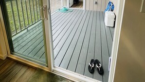 A balcony with a sliding glass door, a wooden deck, and a pair of shoes. - Big Island Green Sands House (Naalehu)