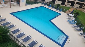 Une piscine rectangulaire bordée de bleu, entourée de chaises longues et d’une petite table avec des chaises.