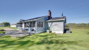 A single-story house with a covered porch, a chimney, and a satellite dish. - 600' of Green Bay Frontage & Dock: Cozy Cottage (Oconto)