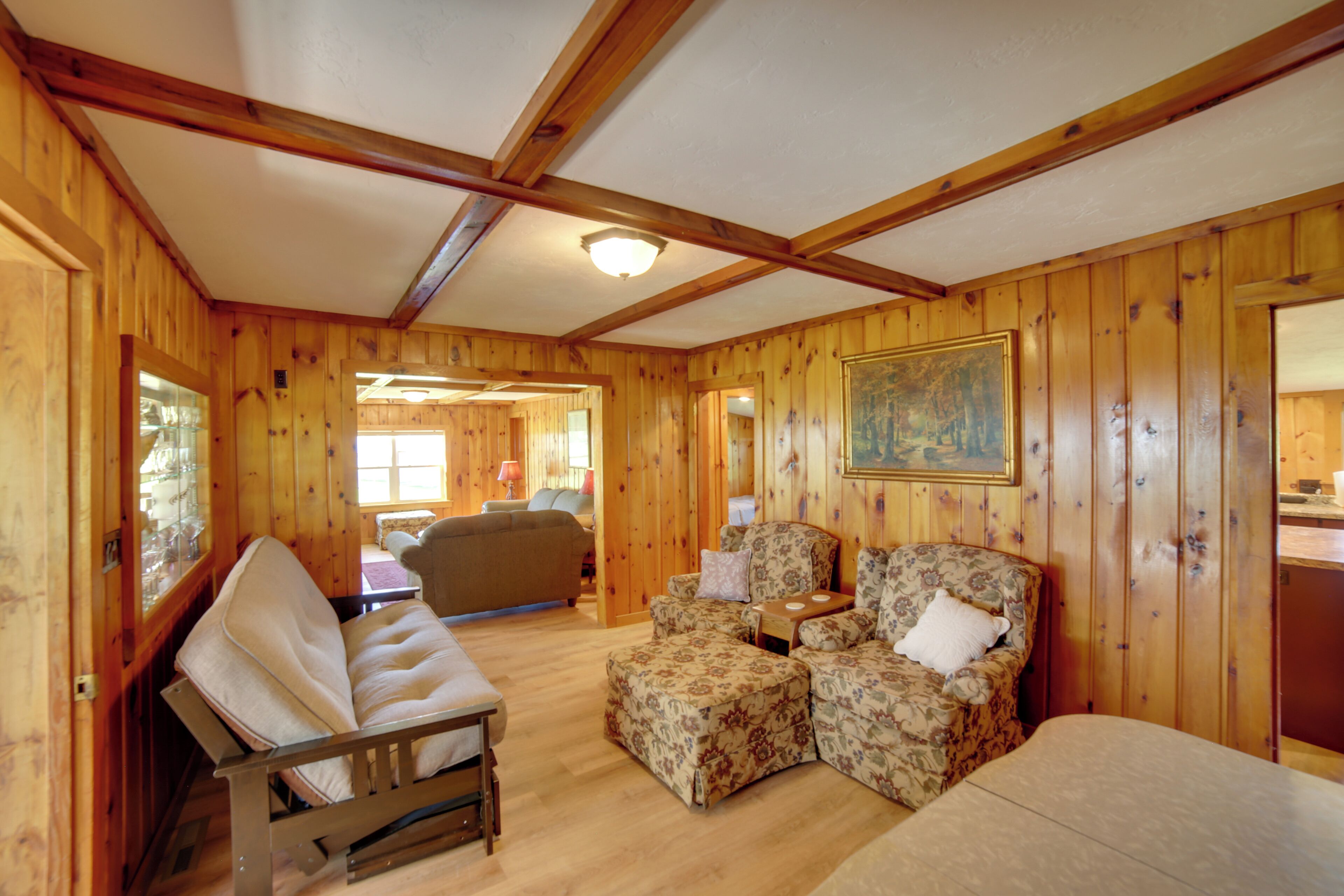 A wooden interior with a sofa, two armchairs, and a dining table.