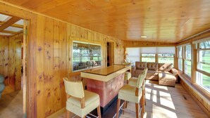 A wooden interior with a bar area, seating, and large windows. - 600' of Green Bay Frontage & Dock: Cozy Cottage (Oconto)