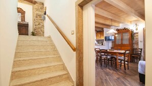 Una escalera conduce a un comedor con piso de madera y pared de piedra.