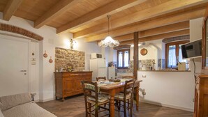 Una sala de estar acogedora con chimenea, una mesa de comedor de madera y un televisor montado en la pared.