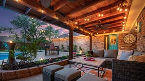 An outdoor patio area with wicker furniture, string lights, and a brick wall.