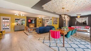 A modern living room with a sectional sofa, a dining table with chairs, and a fireplace.