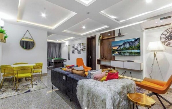 Relax in this stylish living room with a sofa, armchairs, and a mounted TV.