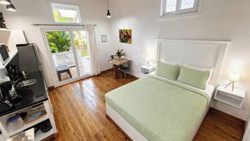 Quarto com cama, escrivaninha e vista para o exterior.