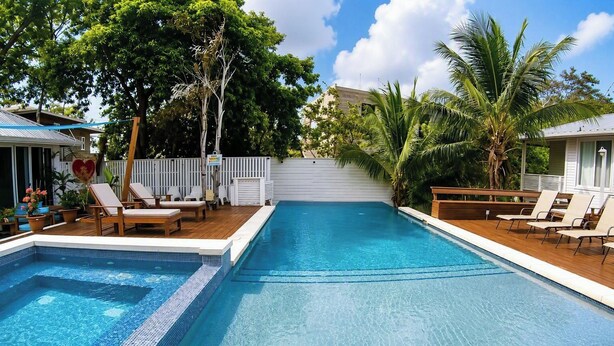 A rectangular swimming pool with a wooden deck and lounge chairs on both sides. - Adorable studio style casita with all the comforts (West Bay, Roatán)